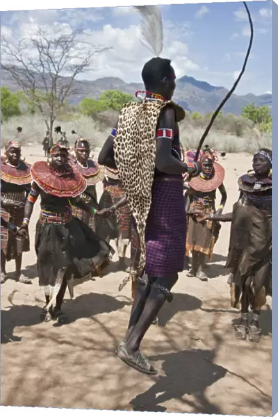 A Pokot warrior wearing a leopard skin jumps high in the air surrounded by women to celebrate an Atelo ceremony. The Pokot are pastoralists speaking a Southern