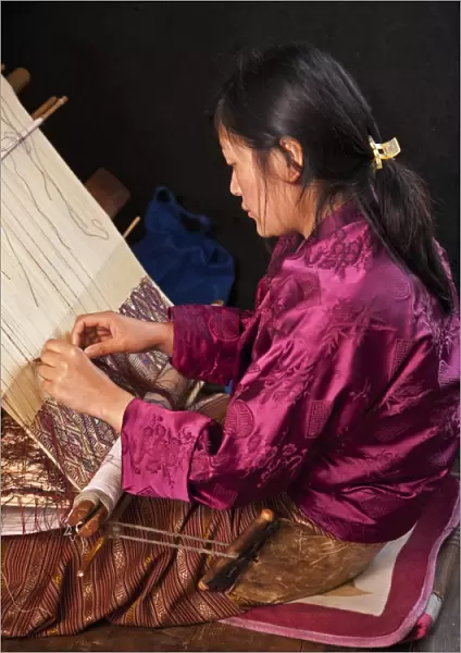 A woman weaves an intricate pattern in silk on her traditional wooden loom. The broad leather belt around her buttocks is the reason for naming this particular type of loom backstrap loom