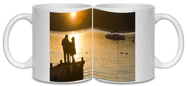 A couple on a jetty at sunset at Waterhead Ambleside UK