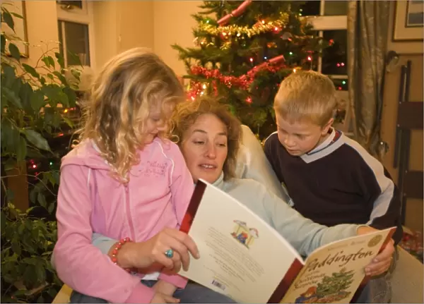 An auntie reads a christmas story to her neice and nephew at christmas time