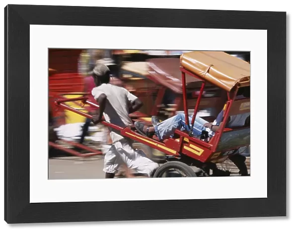 20079233. MADAGASCAR Antsirabe Rickshaw driver traveling along road in motion blur