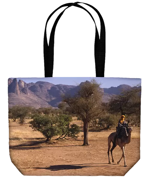 20042817. MALI Sahel Desert Touareg man on camel passing the Dyounde Mountains
