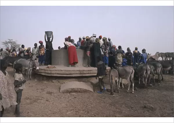 20061366. BURKINA FASO Sahel Crowds of people with donkeys collecting water from well
