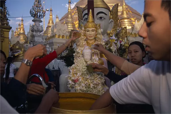 MYANMAR, Yangon People making offerings of flowers and water at shrine in Shwedagon