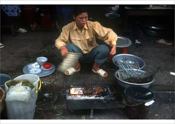 20002462. Vietnam, Hanoi, Woman cooking at curb side food stall