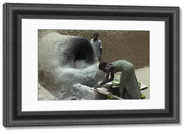 20075145. MALI Timbuctu Girl making bread using outside clay oven