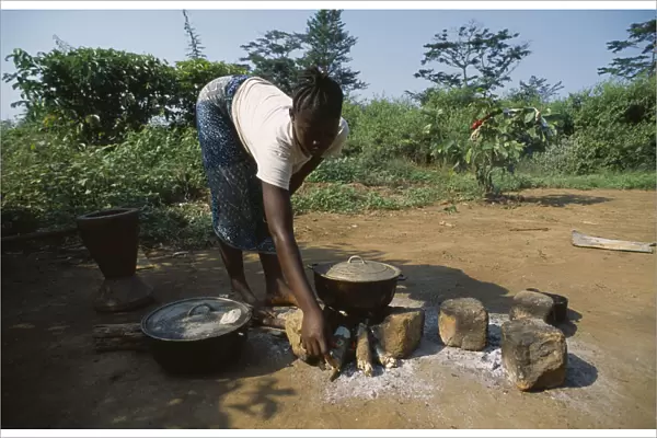 20064179. LIBERIA Nimba Saclepea Young woman cooking on open wood fire