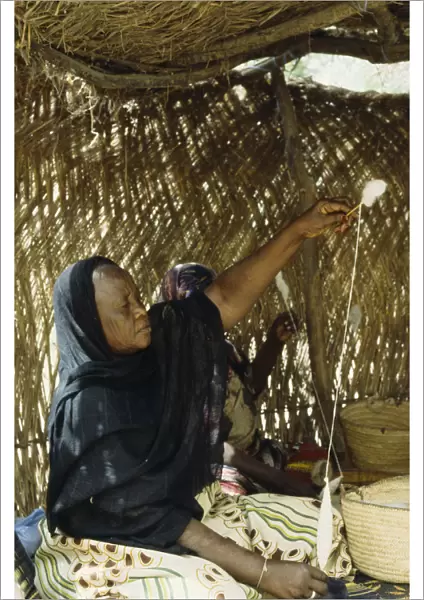 20075604. CHAD N Djamena Woman spinning cotton inside straw hut