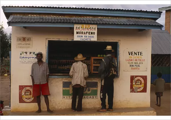 20079305. MADAGASCAR Ihosy Men standing at a kiosk which sells rum and beer