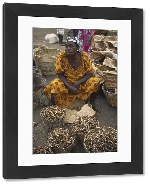 20075477. GHANA Accra Female vendor with baskets of dried fish for sale at market