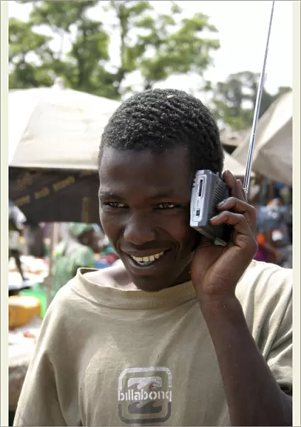 Albert Market Russell Street. Young African man smiling while listening to a radio which he is holding next to his ear
