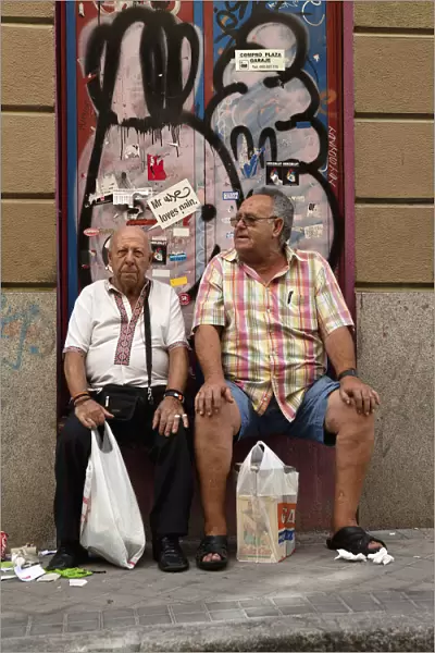 Spain, Madrid, Two visitors to the El Rastro Flea market take a rest from shopping