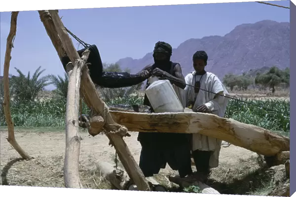 20075116. NIGER Air Mountains Tuareg filling water bottles for agricultural use. toureg