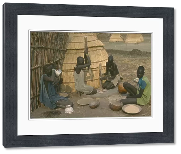20073150. SUDAN Agriculture Dinka women pounding millet outside their hut
