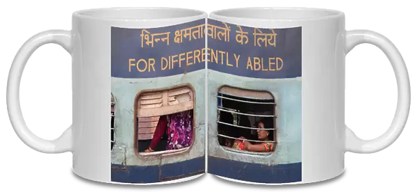 India, West Bengal, Asansol, Passengers at the window of a train carriage for the differently abled at railway station