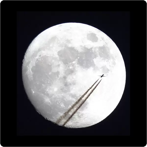An aircraft passes in front of the moon above Manchester