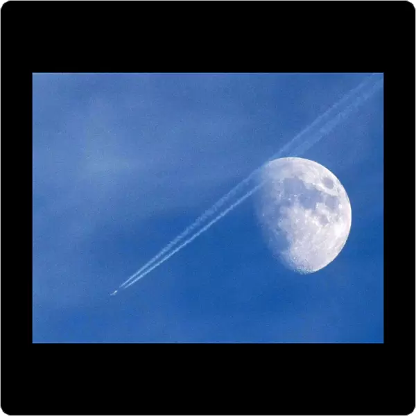 A passenger plane leaves a contrail as it flies past the moon over Malta