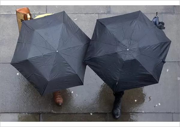 People shelter under umbrellas as they walk through central London