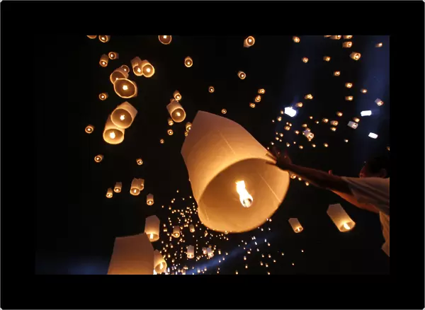 People launch floating paper lanterns into the sky to celebrate Thai King Bhumibol