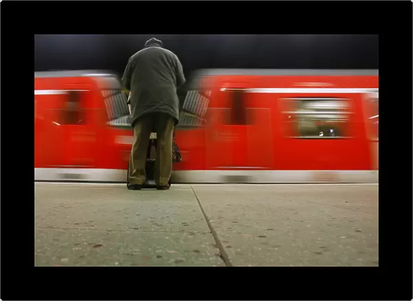 Passenger waits on a platform as a suburban train leaves the platform during a strike