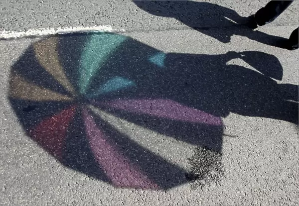 The shadow of an umbrella is cast on the ground during the annual gay pride parade