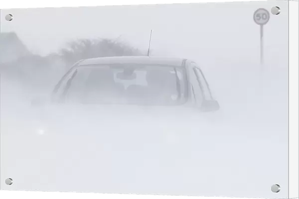 A motorist drives through snow blown from fields near Buxton in central England