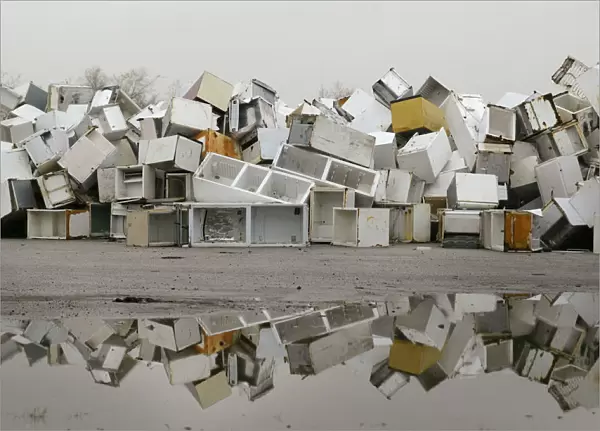 Disused fridges and freezers lie piled up in a storage yard in Manchester