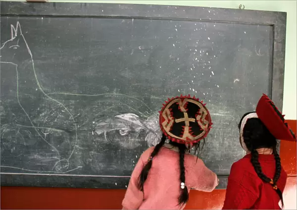 Andean girls in traditional Inca clothes draw a llama in school in the village of