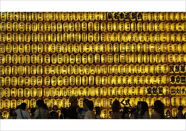 People walk in front of paper lanterns during the Mitama Festival at the Yasukuni
