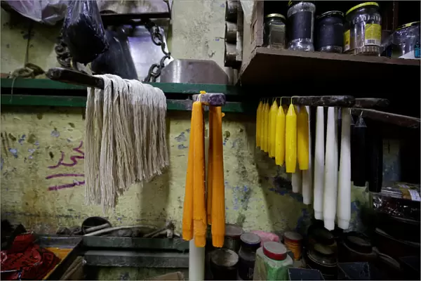 Different types of coloured candles hang on wooden boards for cooling at Haj Mohamed