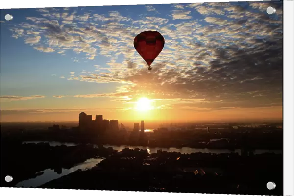 A hot air balloon rises into the early morning sky in front of the Canary Wharf financial