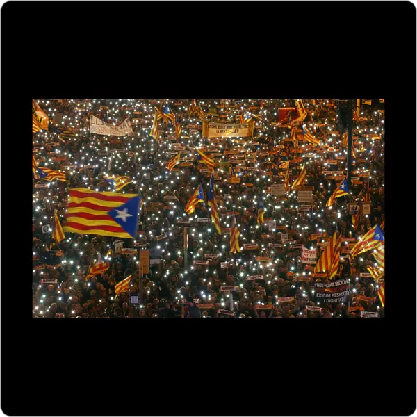 Protesters hold the lights of their mobile phones as they wave Estelada flags during a