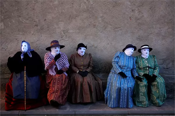Revellers dressed as Mascaritas sit during carnival celebrations in the village of