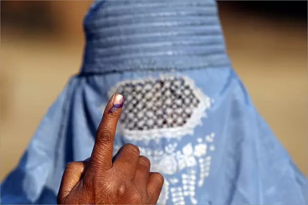 A woman shows her ink marked finger after voting during the state assembly election