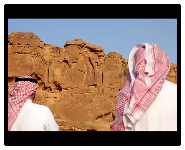 Men look at a camel sculpture carved on a rock in Al-Jouf