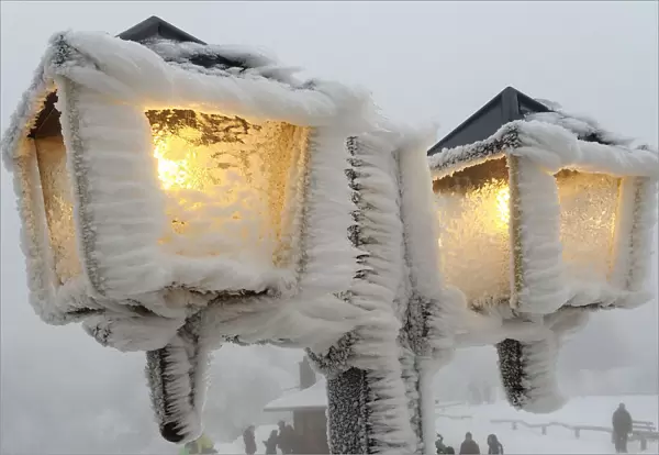 Streetlamps are covered in snow and ice outside a restaurant on the peak of the Feldberg