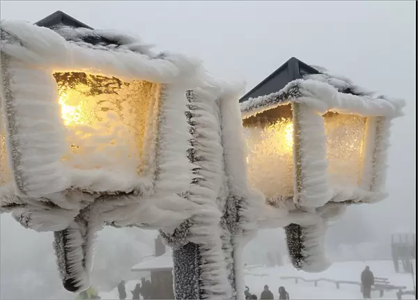 Streetlamps are covered in snow and ice outside a restaurant on the peak of the Feldberg