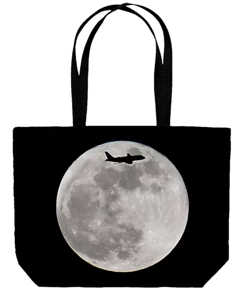 A passenger plane flies in front of a supermoon full moon over London