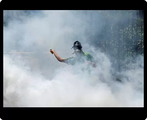 Palestinian protester hurls stones towards Israeli troops as he reacts to tear gas during