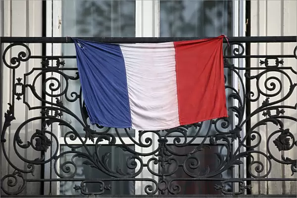 A French flag hangs from a balcony in Paris to pay tribute to the victims of the Paris