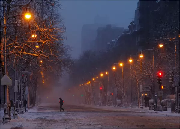 A pedestrian crosses Beacon Street as snow begins to accumulate in Boston