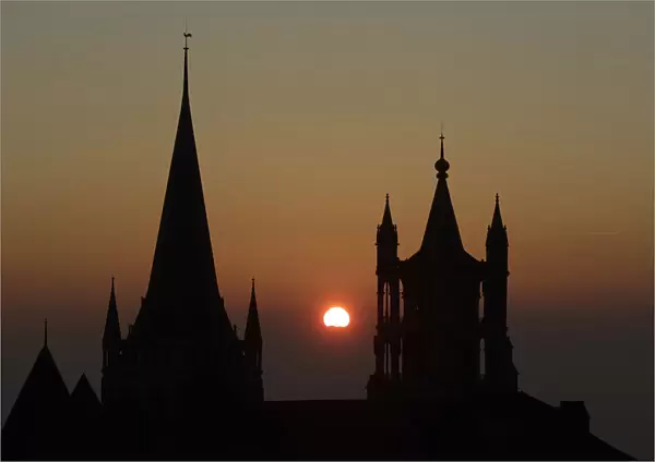 The sun sets on a winter evening between the spires of the Cathedral of Notre Dame in
