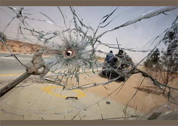 Libyan rebels manning a checkpoint near the front line are seen through a bullet-pocked