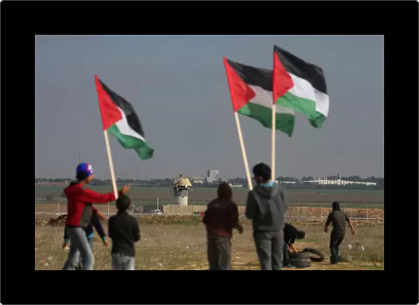 Demonstrators hold Palestinian flags during clashes with Israeli troops near the border