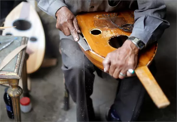 Artisan Mohammed Karam works on an oud in front of a workshop in Cairo