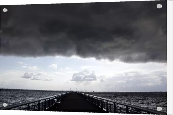 Dark clouds fill the Autumn sky over the jetty in Andernos, southwestern France