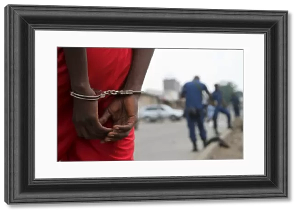 A suspect is handcuffed and detained by policemen after a grenade attack of Burundi s