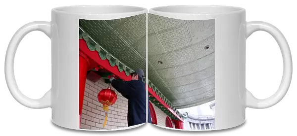 A man hangs a lantern for the Chinese Lunar New Year at Mahayana Buddhist Temple in