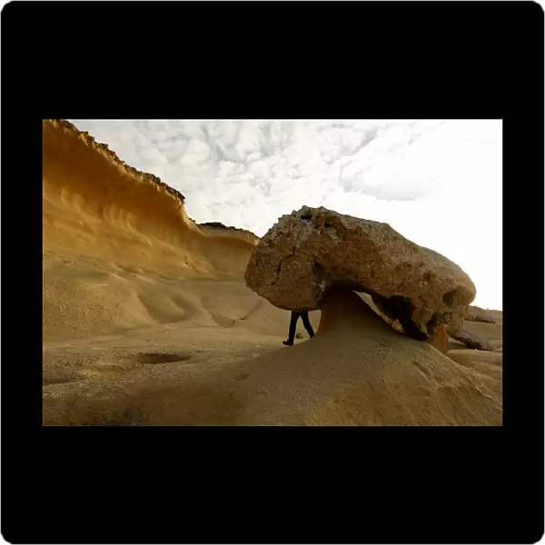 A tourist hikes past the so-called Mushroom Rock, formed by years of weathering