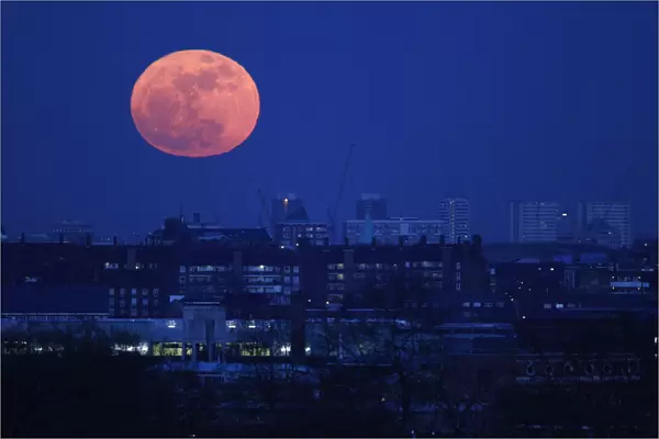 The moon rises over east London